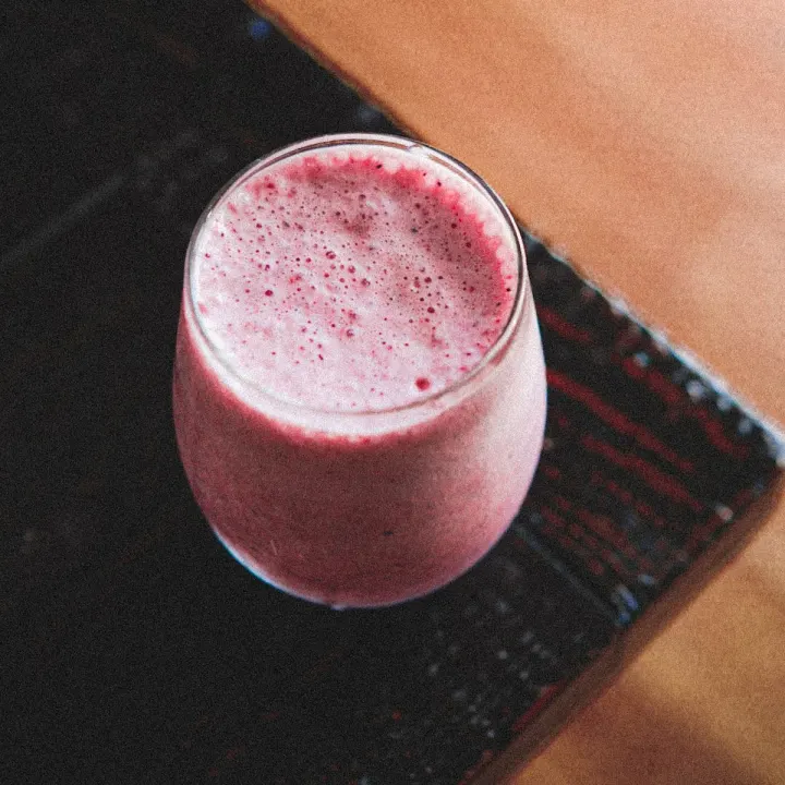 A berry smoothie in a glass on a wooden table