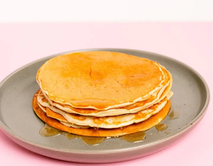 A stack of pancakes with syrup on a grey plate