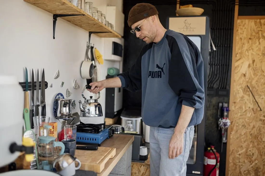 A man making coffee in a small kitchen